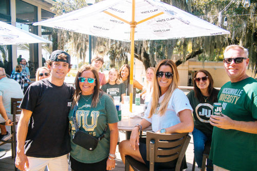 Parents and Students under an outdoor umbrella sipping cold drinks.