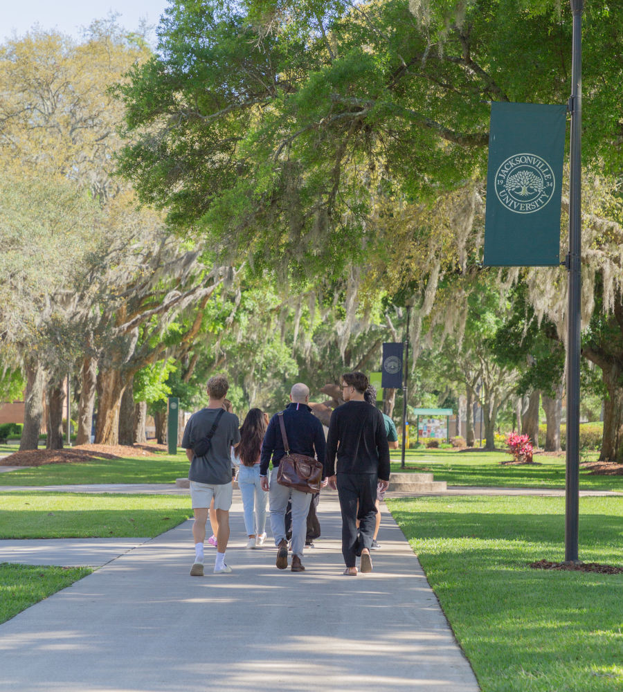 5 students walk on Jacksonville University's Dolphin Drive. 