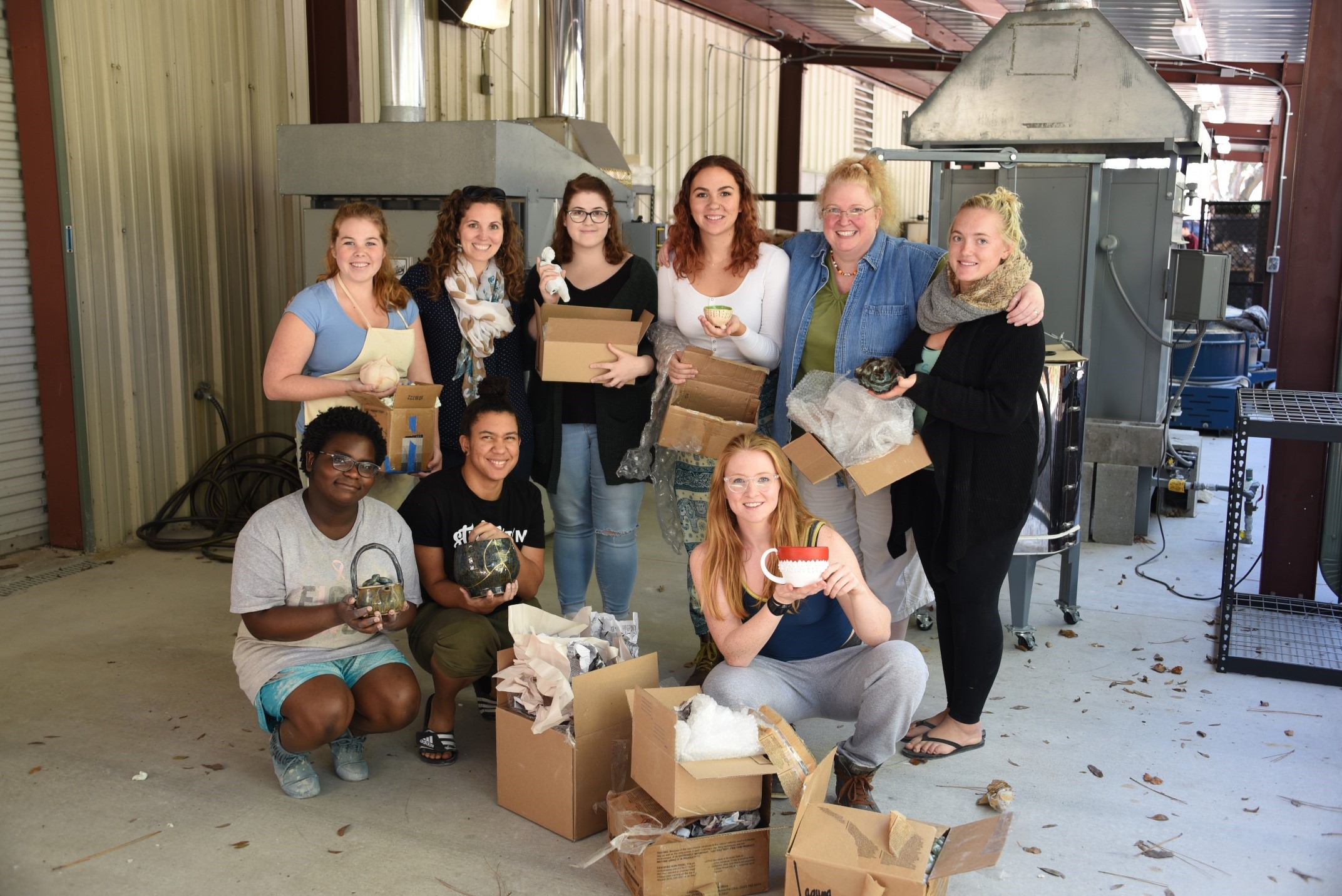 Dana Tupa with a group of students and their clay work