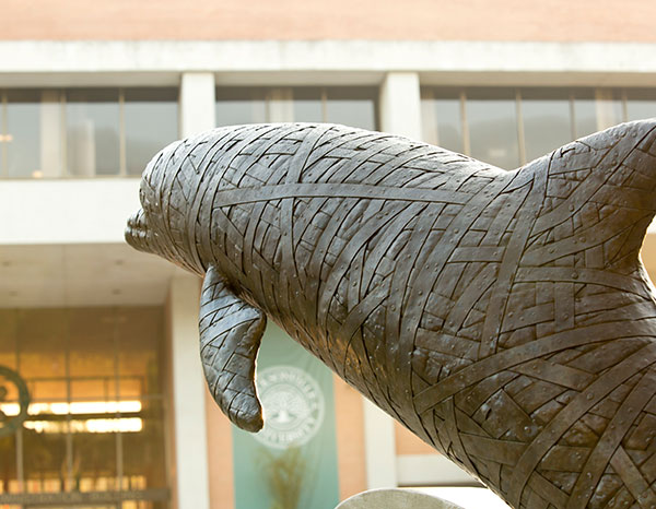 One of the dolphin statues with the Howard Administration Building in the background.