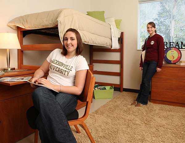 Two female roommates pose in their dorm room.