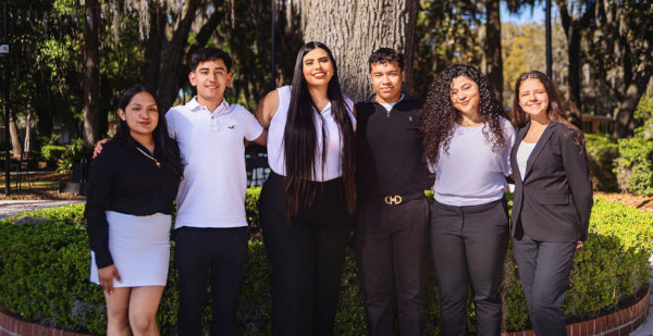 a group of students pose in front of a garden tree at Jacksonville University
