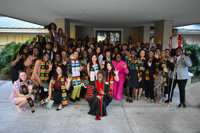A large group of diverse people posing for a photo in front of a building. 