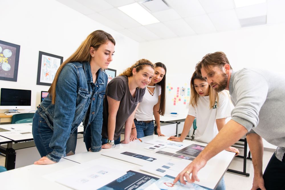 male teacher with female students in a design lab