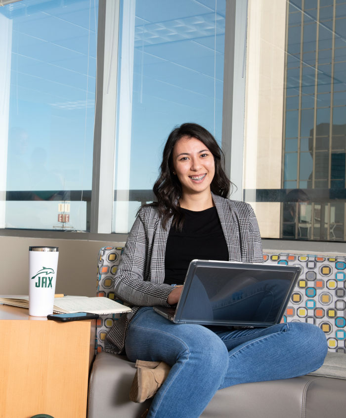 A student sitting on a couch with laptop on her lap.