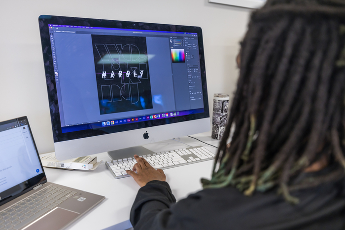 Graphic design student utilizing Adobe graphic design programs on a computer