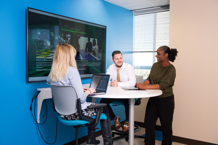 Three professionals with laptops in a meeting